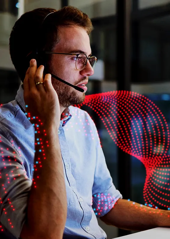 Man speaking on a headset whilst looking at a computer 