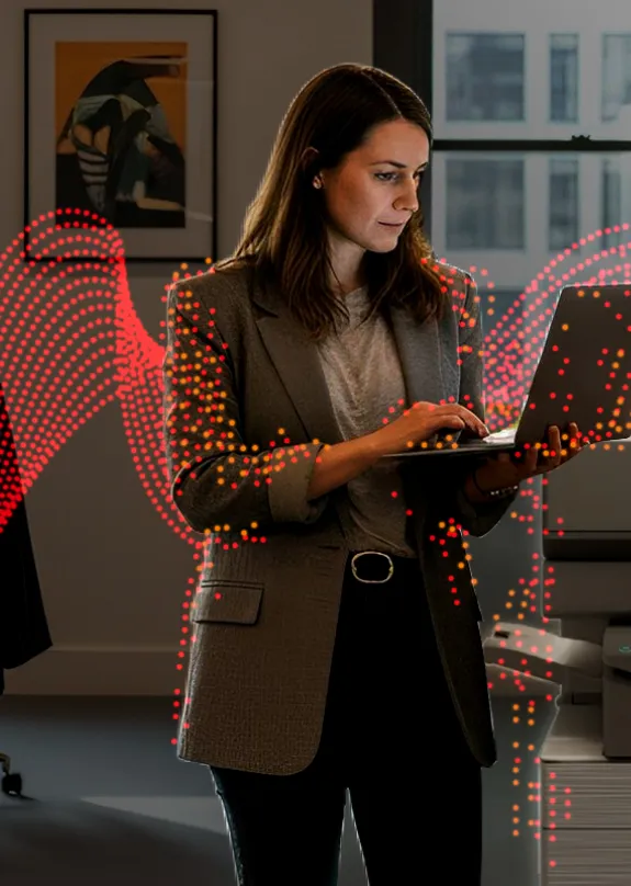 Woman typing on a laptop next to a Sharp MFP 